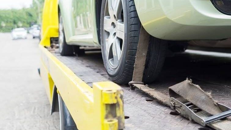 een groene auto die op een sleepwagen staat