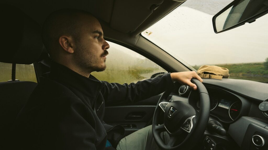 Leerling rijdt geconcentreerd tijdens rijles in regenachtig weer, voorbereiding op rijexamen plannen