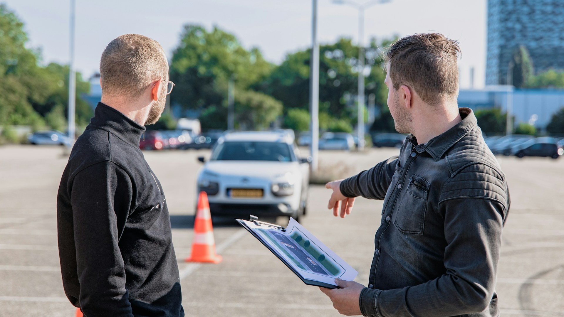 Rijinstructeur bespreekt examenroute met leerling op oefenterrein als onderdeel van rijexamen plannen