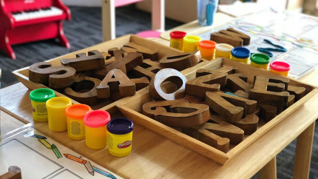 Houten letters en klei op tafel in kinderopvang waar ouders opvanguren opvoeren voor toeslag