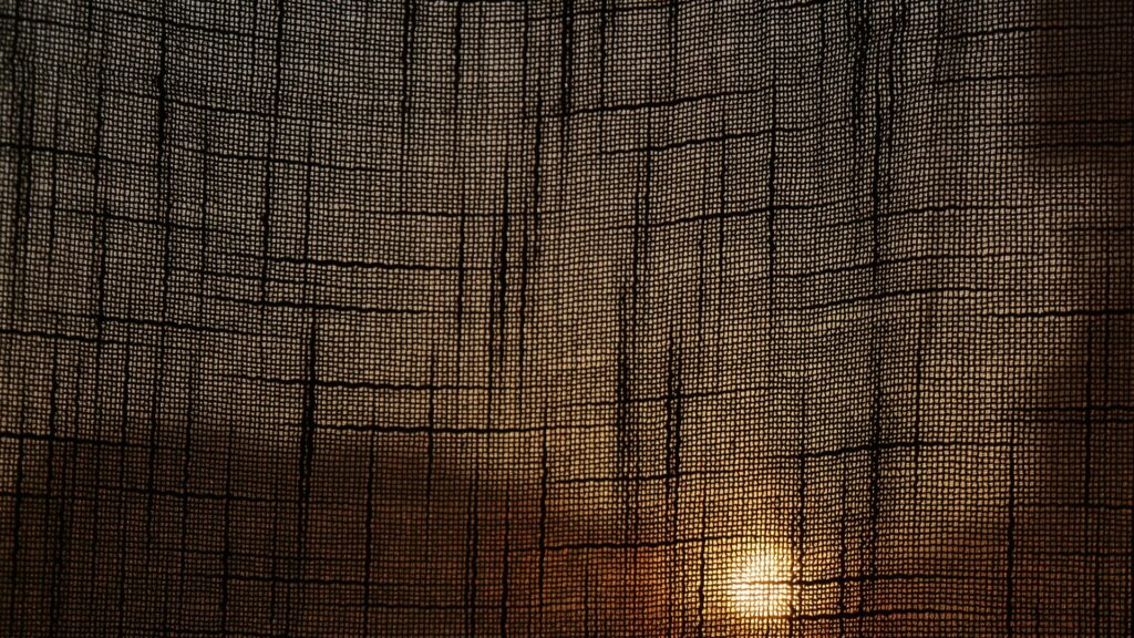 Buitendoek ophangen met fijn gaasdoek tegen laagstaande zon en warme gloed bij zonsondergang