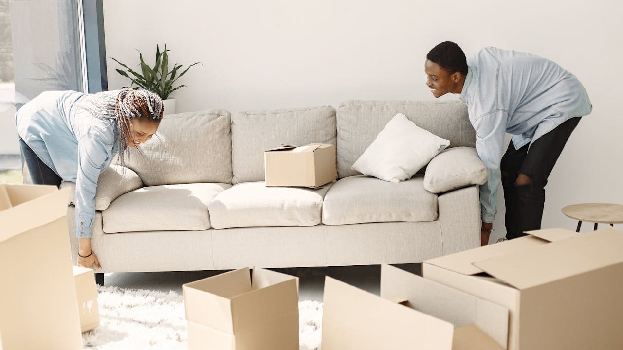 Twee personen tillen bank tijdens woning leeghalen en voorbereiden op oplevering