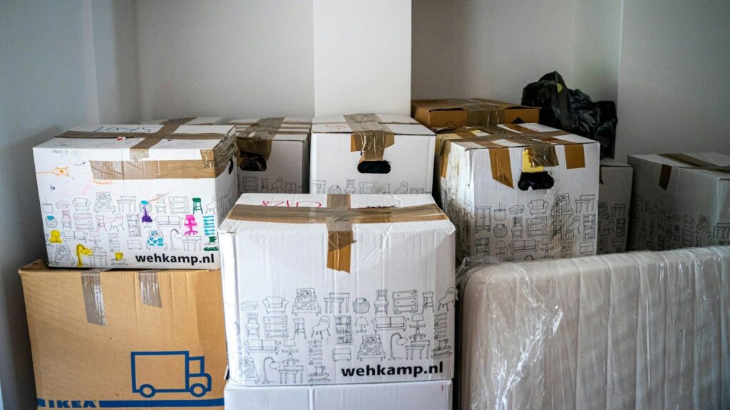 Verhuisdozen gestapeld in lege woning tijdens woning leeghalen na huurbeëindiging