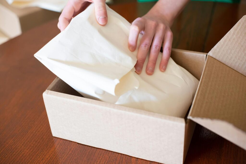 Handen pakken ingepakt product uit kartonnen verzenddoos op tafel