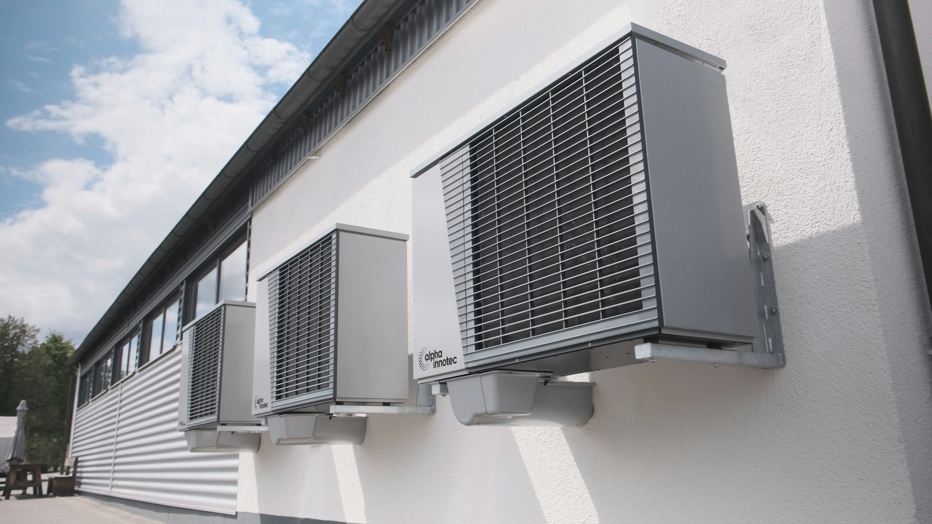 Drie airco buitenunits aan een witte gevel, voorbeeld van een airco ophangen zonder vergunning.